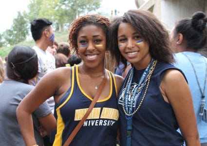 Two students in NAU logo shirts pose during an event.