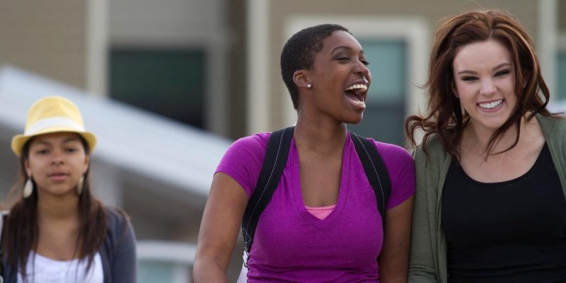 Two students walk on campus, laughing.