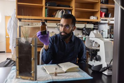 Javier Navarro inspects a jar and writes in a notebook.