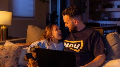 NAU online student works on homework on the couch with his daughter.