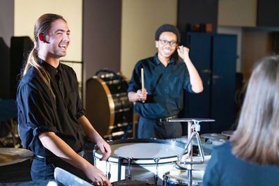 NAU students in the percussion section laugh as they have a jam session in rehearsal.