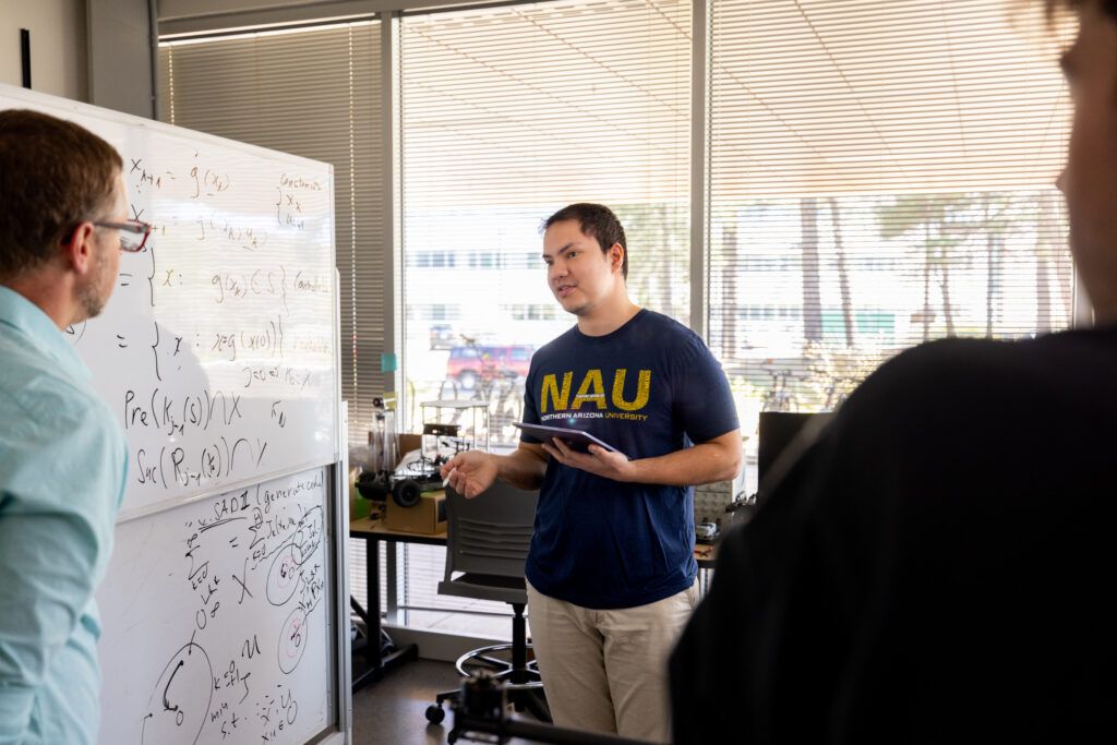 A student and instructor write math equations on a whiteboard.