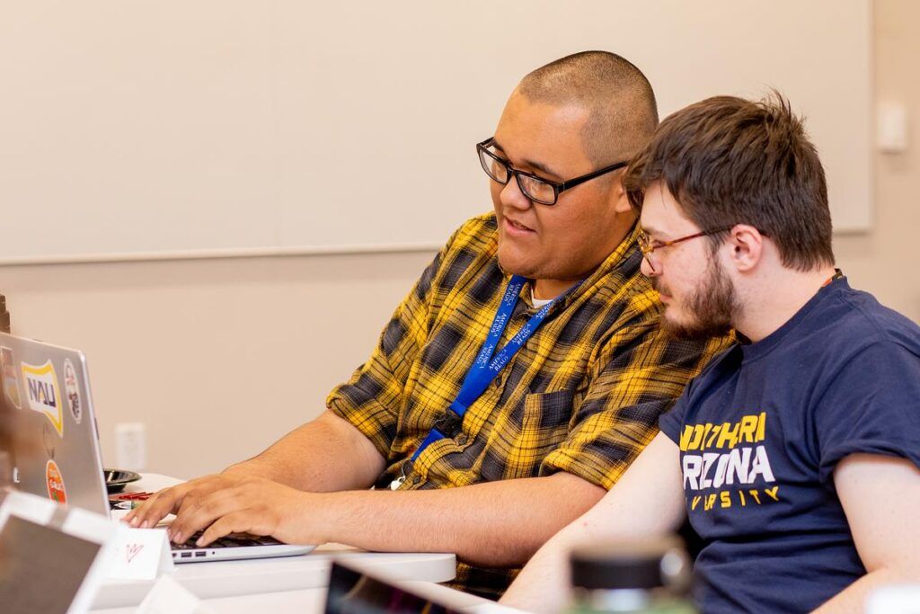 Two N A U students work together on a laptop computer.