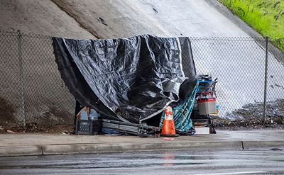 A tarp covering a homeless camp under a bridge.