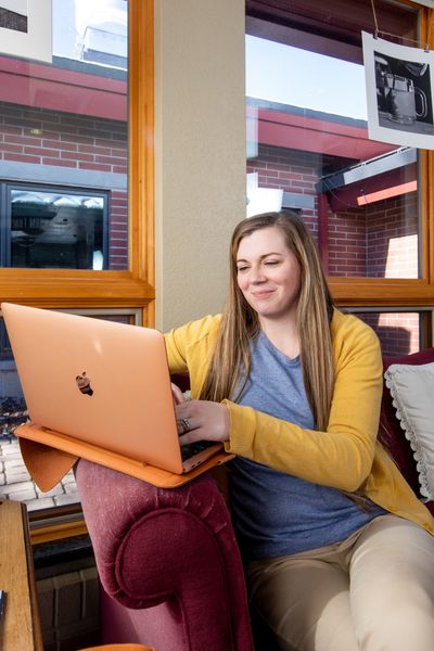 Amber Connolly sits in a comfortable chair while working on her laptop.
