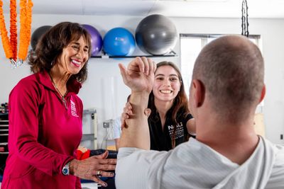 An NAU Physical Therapy student assists a patient with the help of her professor.