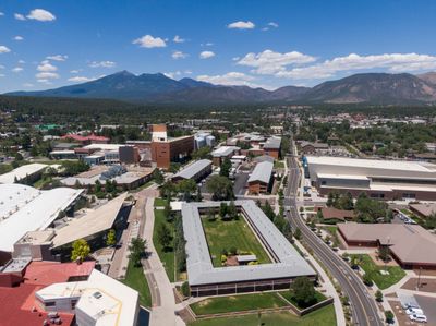 Birds-eye view of N A U campus on a sunny day with Flagstaff and the San Francisco peaks in the background.
