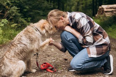 Woman kneeling with a dog and placing her forehead on his