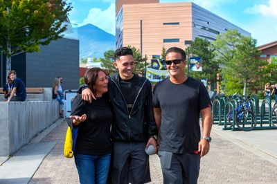 An NAU student smiles with his parents while walking through campus.