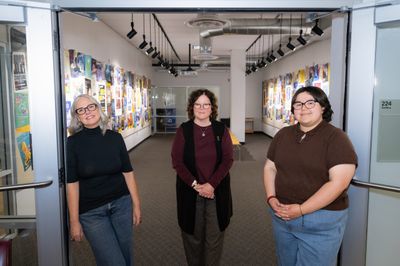 Patricia Murphey, Kathleen M. McGeever and Mia Avelar standing at the entrance of The Long Road Together exhibition at NAU