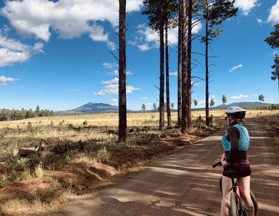 Cyclist standing on top of the bike on a trail.