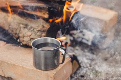 Cup of water on top of a wooden surface surrounded by smoke and fire