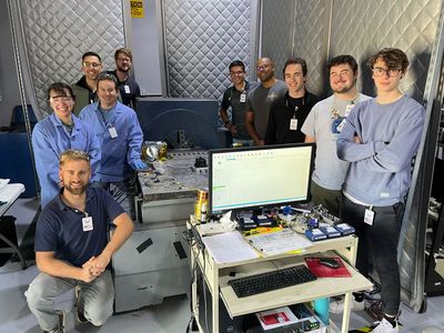 group of students and faculty standing in a lab with cameras and testing equipment