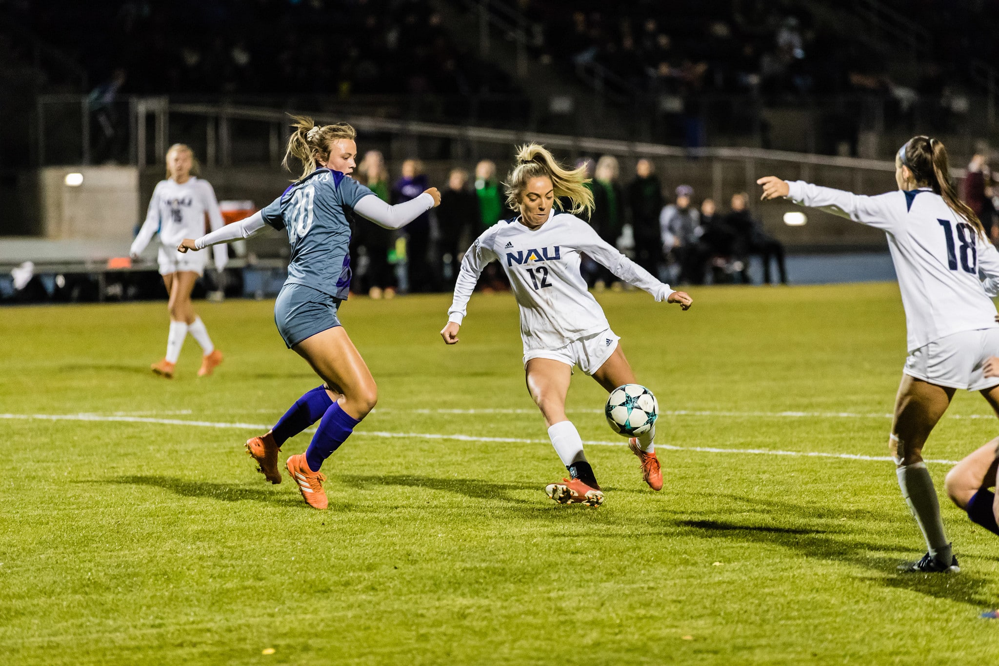 Three soccer players competing for the ball during a women's soccer game