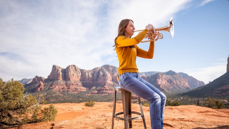 School of Music student sits on still in the middle of the Sedona Red Rock playing a tuba