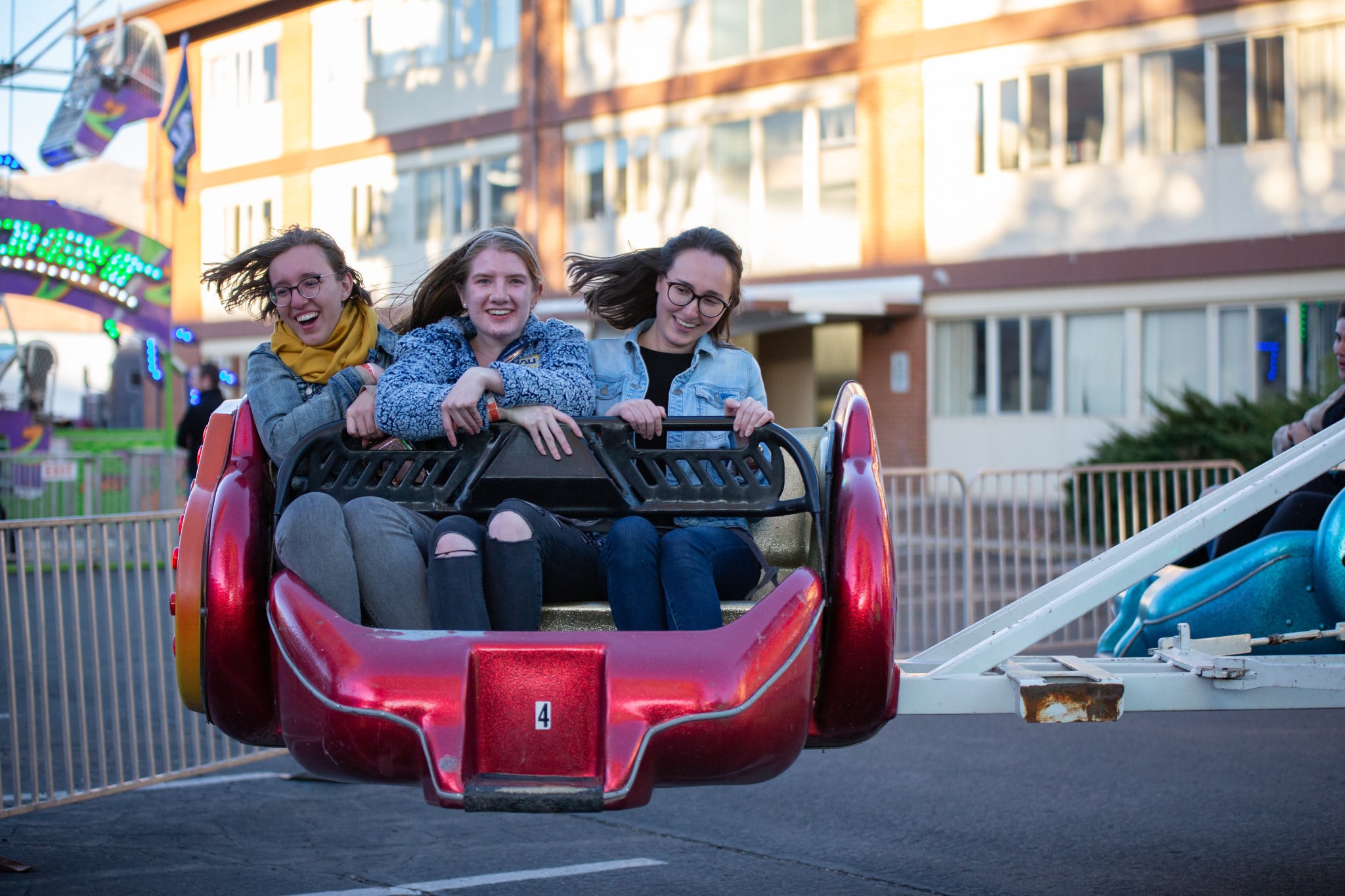 Three students seated together on a ride at the Homecoming carnival