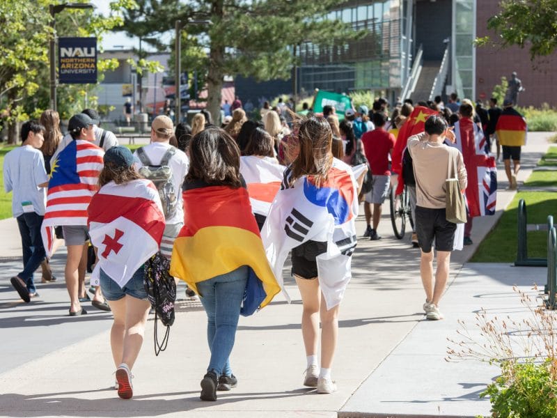 students walking on the pedway with various international flags wrapped around themselves