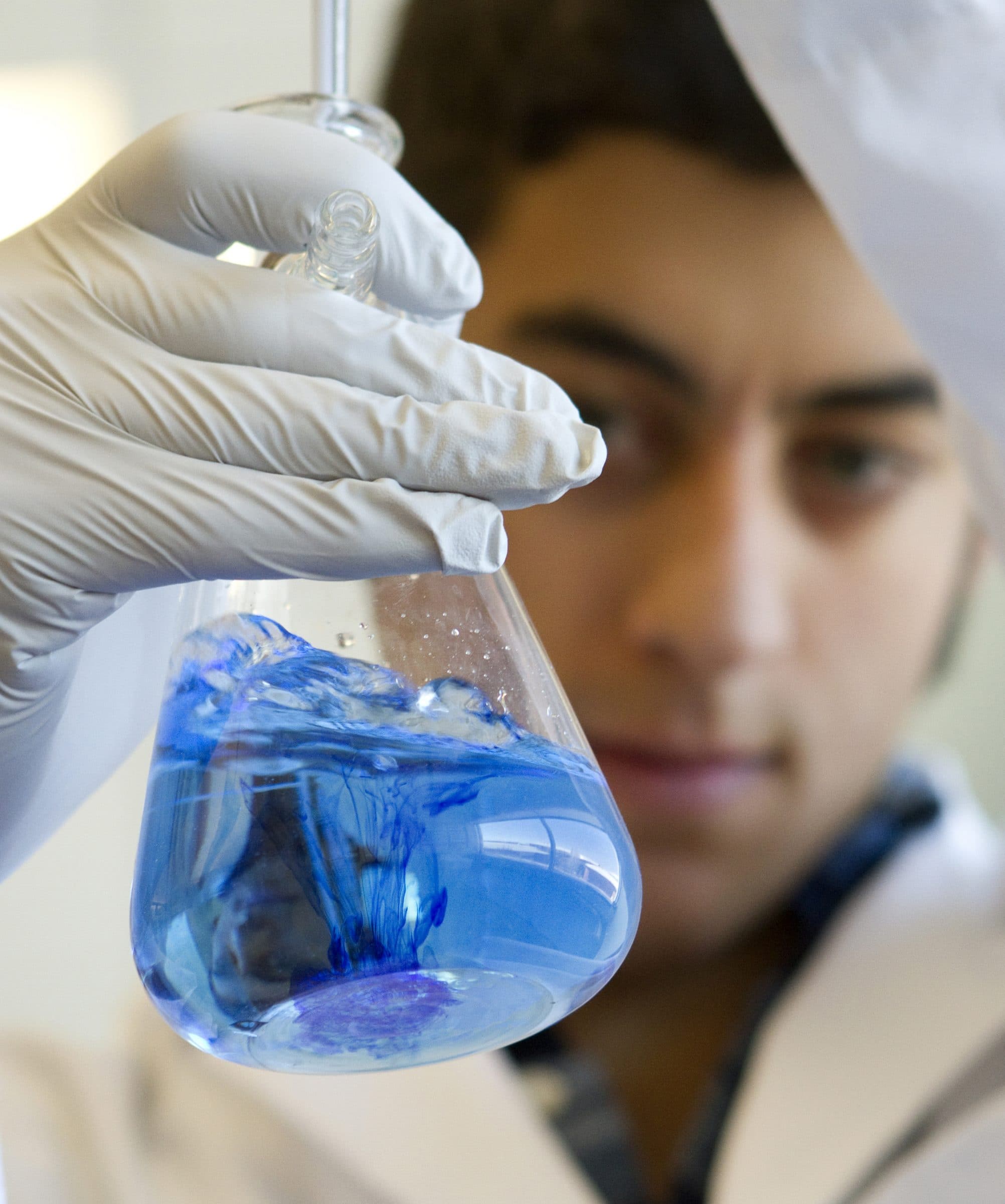A student looking at a vial of blue liquid.