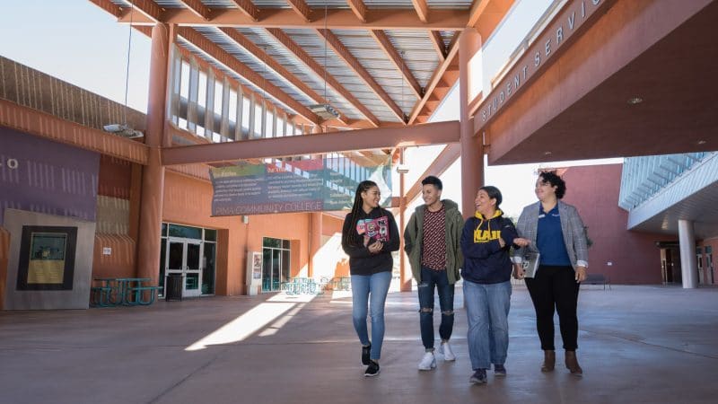 Four students walk on college campus.