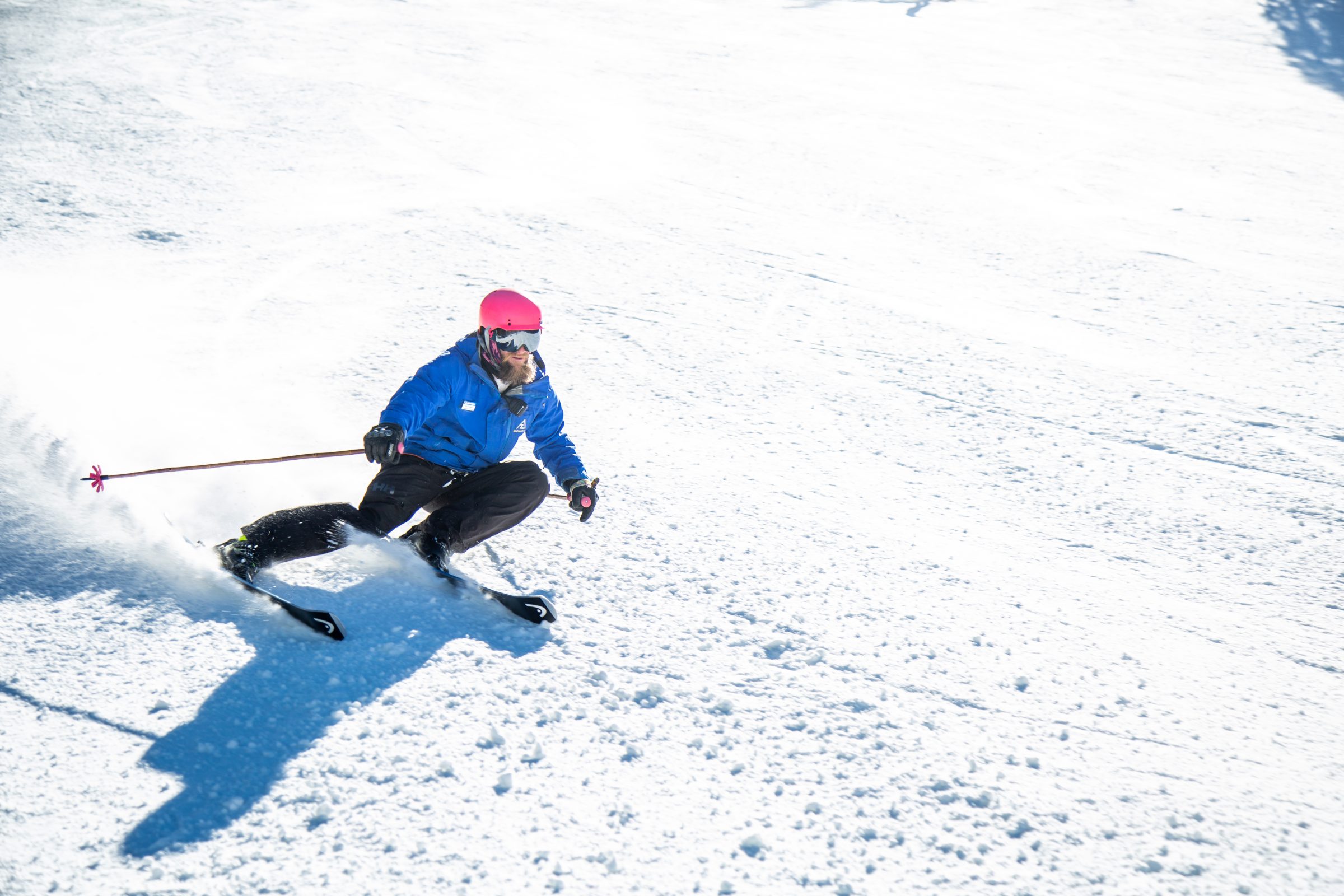 Person in blue jacket skiing down a snowy mountain