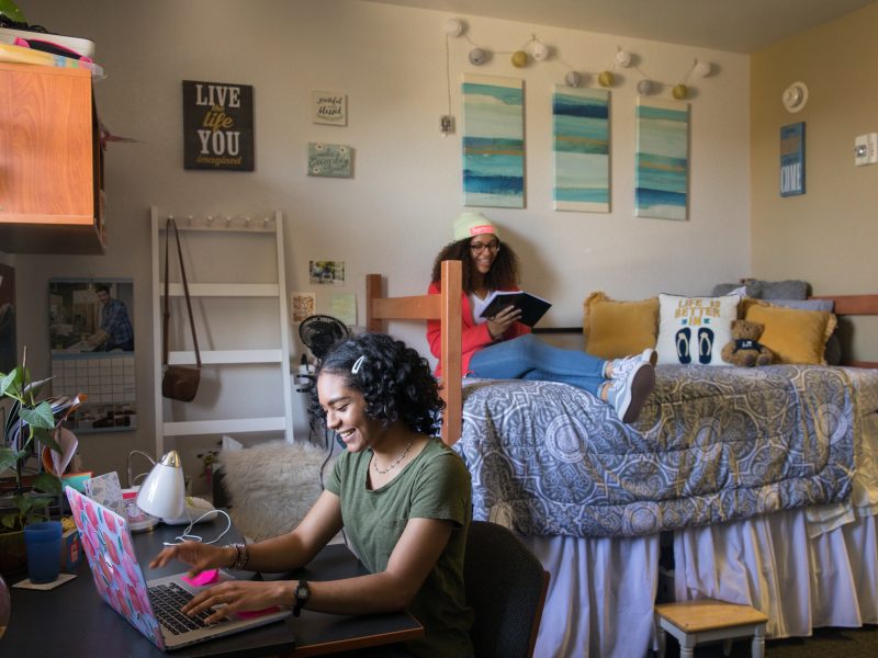 Students smiling while studying in their dorm