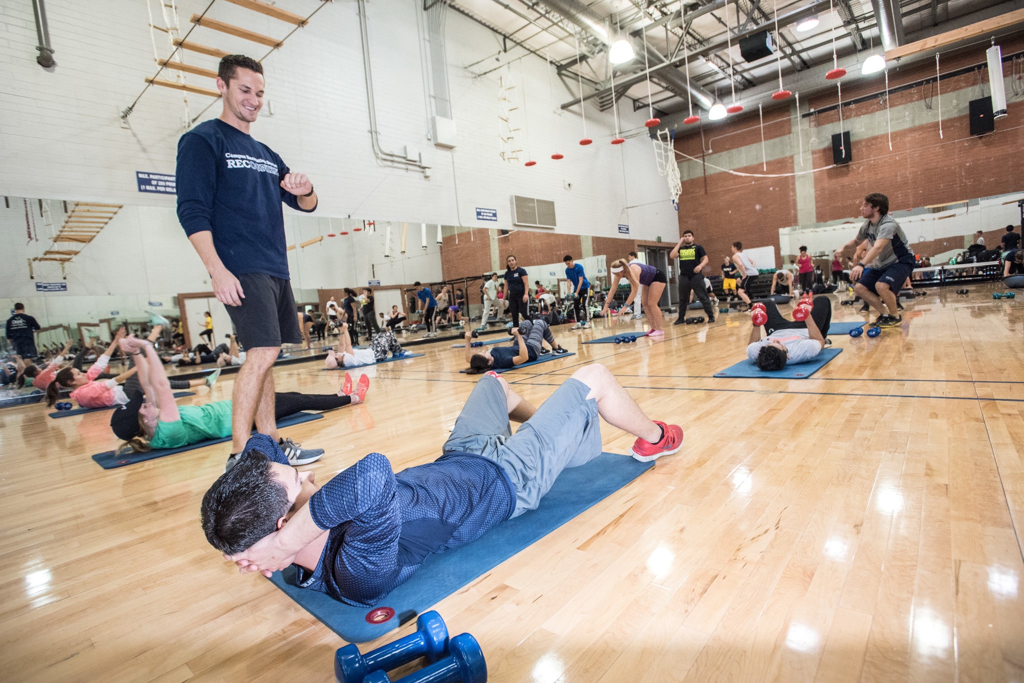 Student does sit ups in gym with instructor.