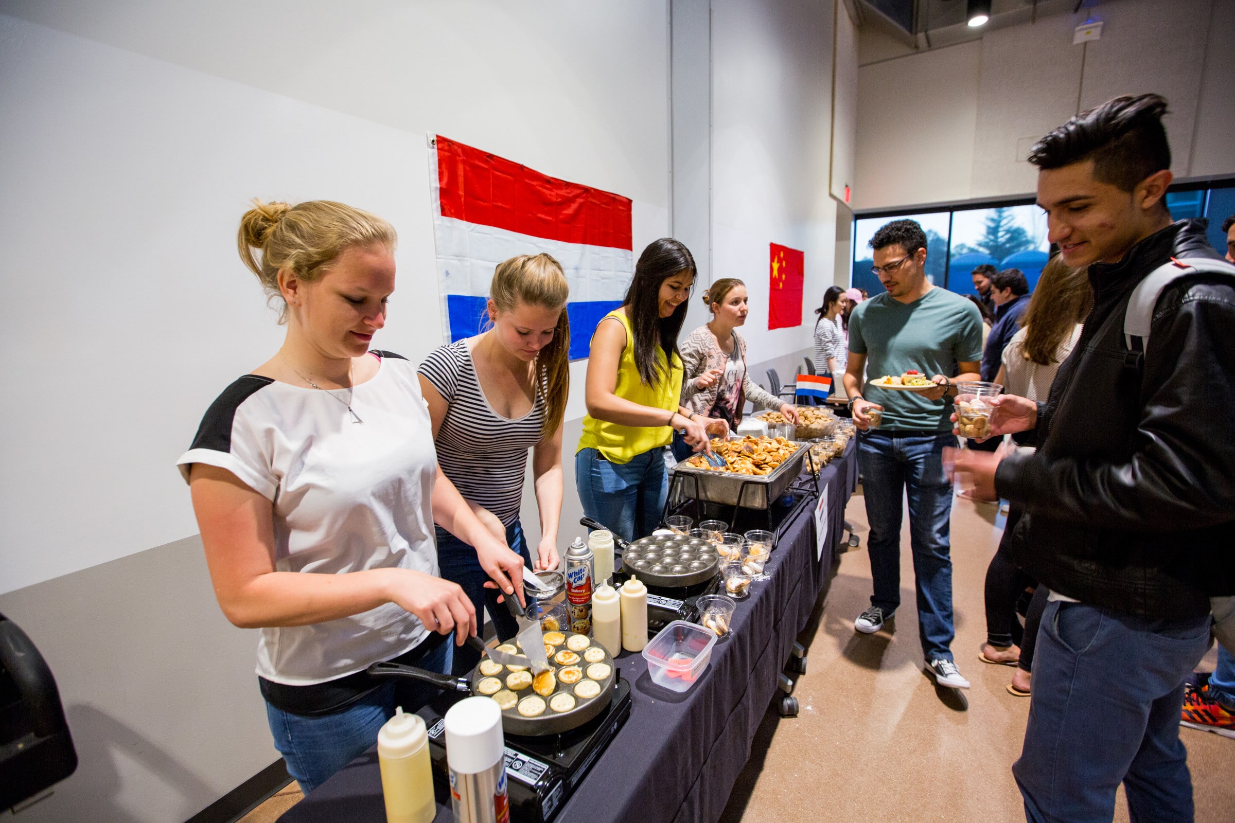 Students serve traditional food in a buffet line.
