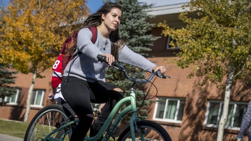 Student rides bike in front of residence hall.