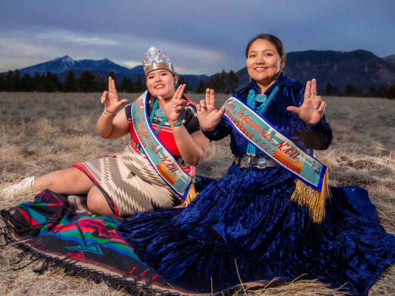 Two Native American women sitting in a field.