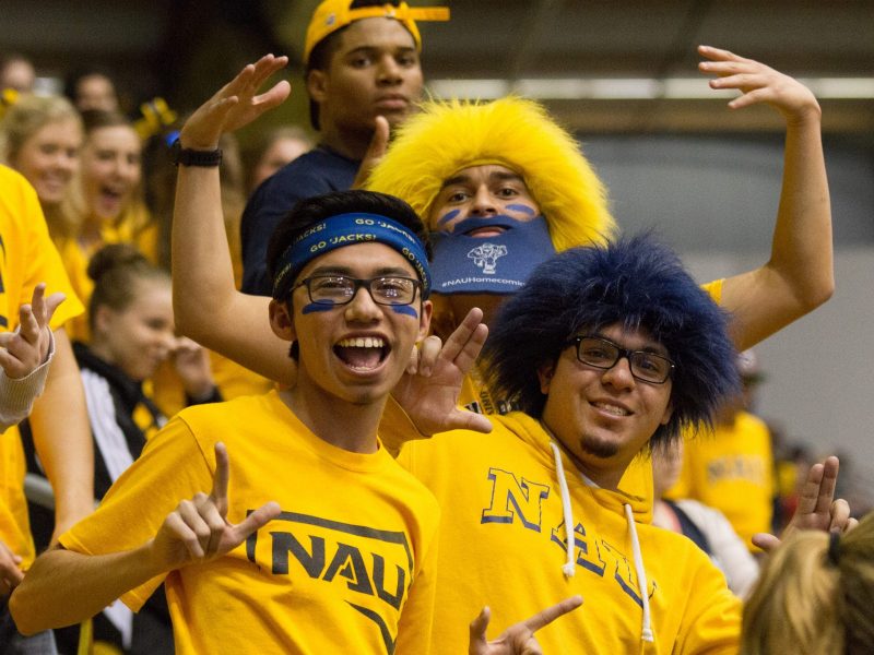 Students dressed in NAU gear in student section at NAU football game.