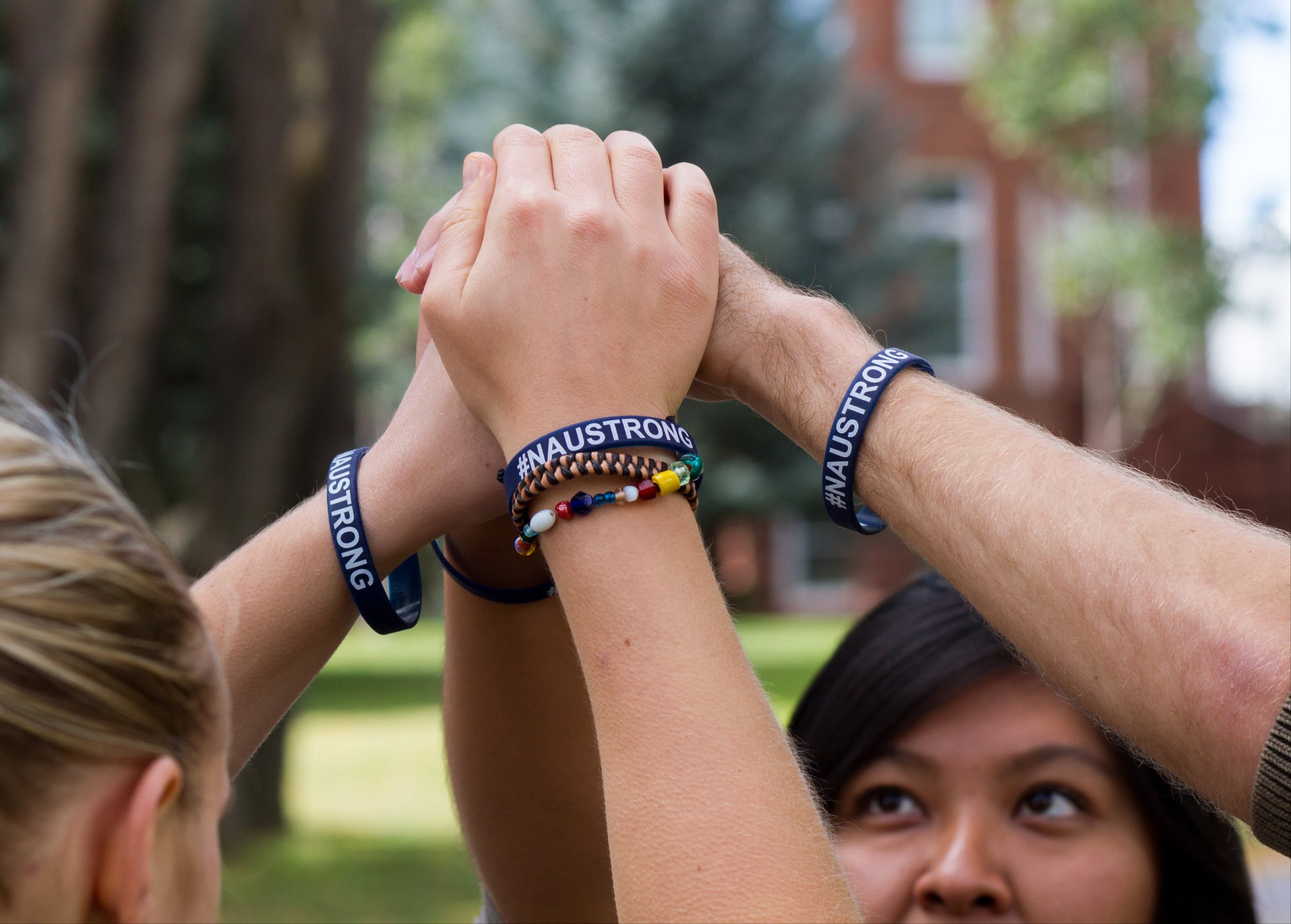 Students with NAU strong bracelets putting their hands together.