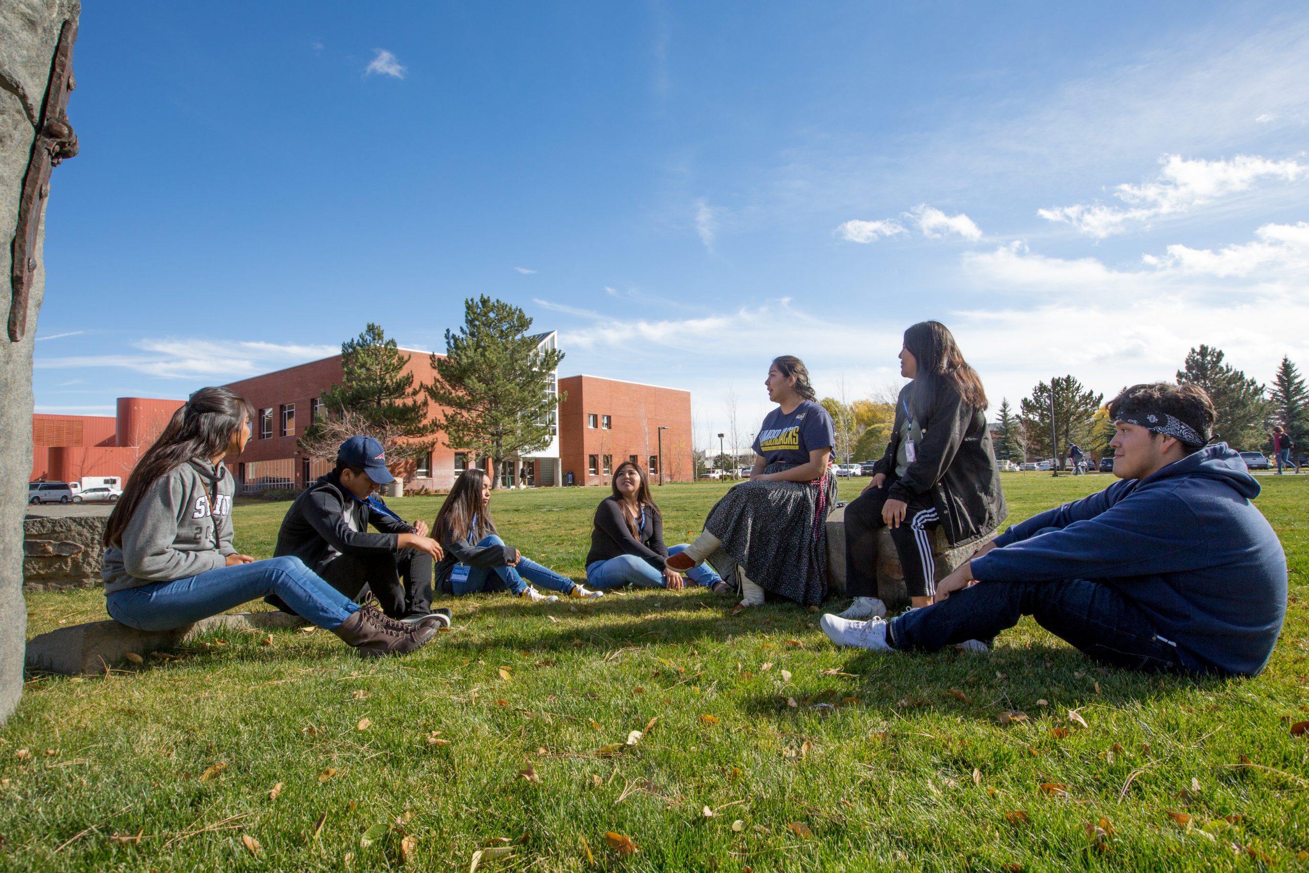 Students sit in a semicircle in the grass on the Flagstaff campus.