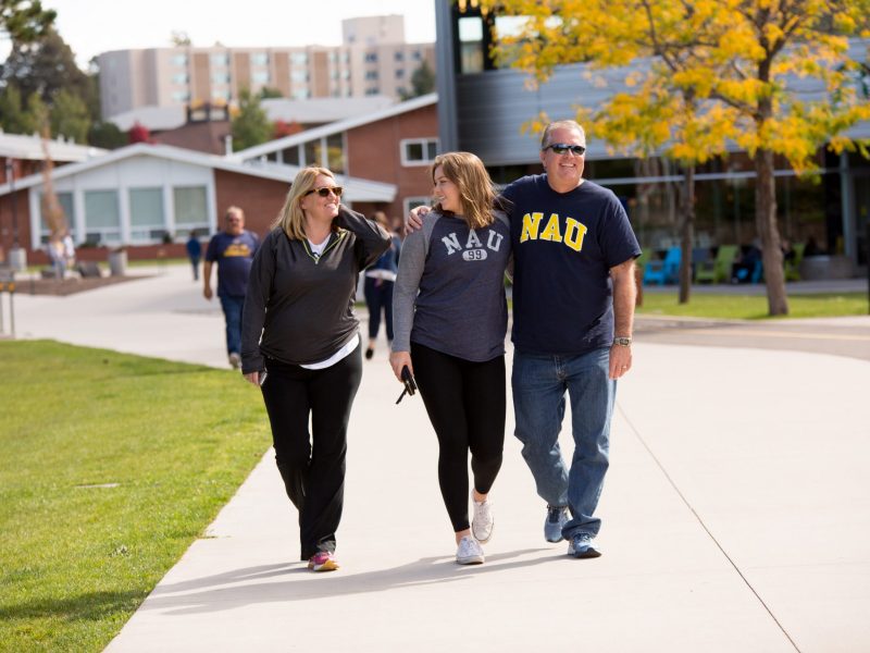 Student walks with their parents on campus.