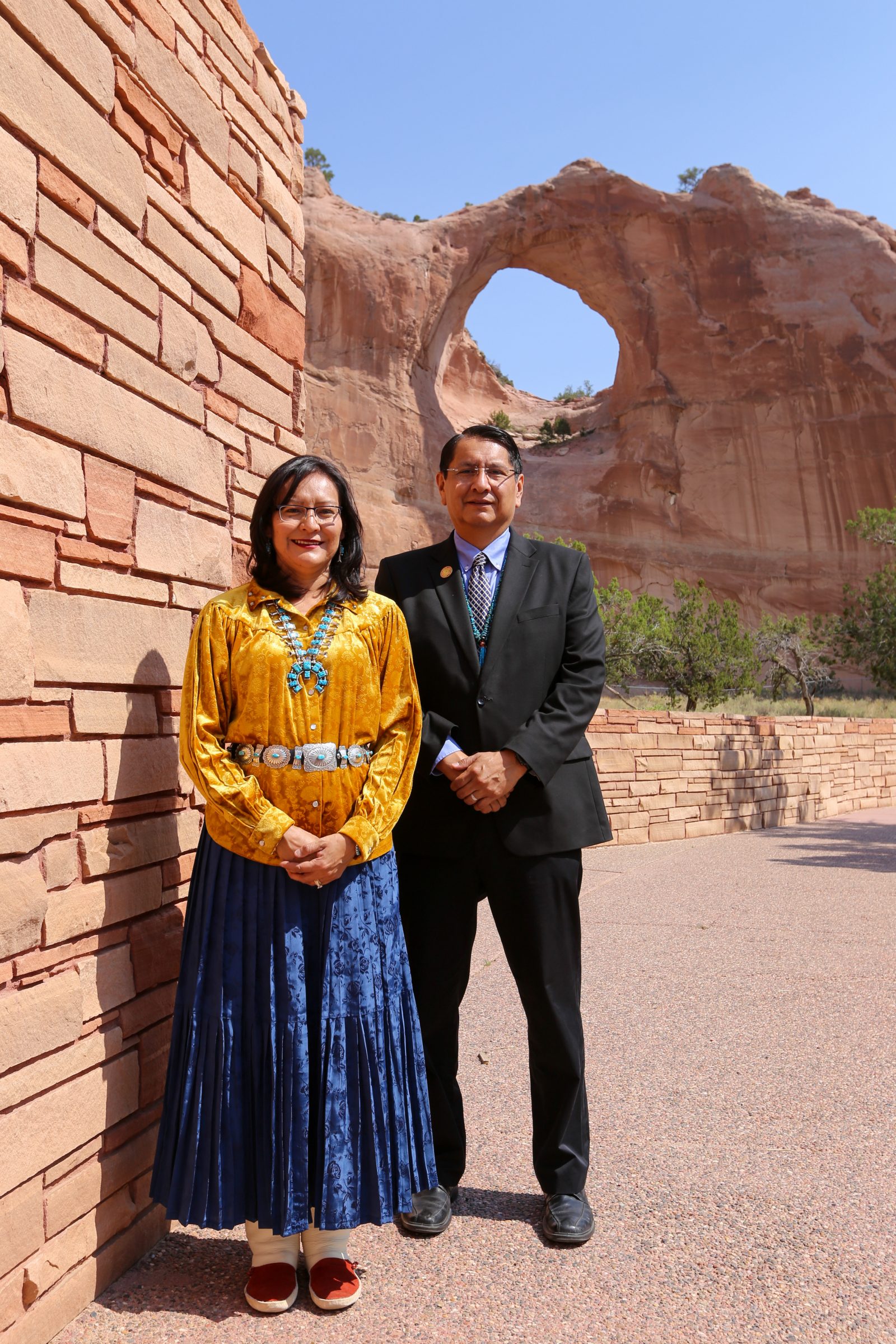 Navajo Nation president and wife stand in front of desert rocks.