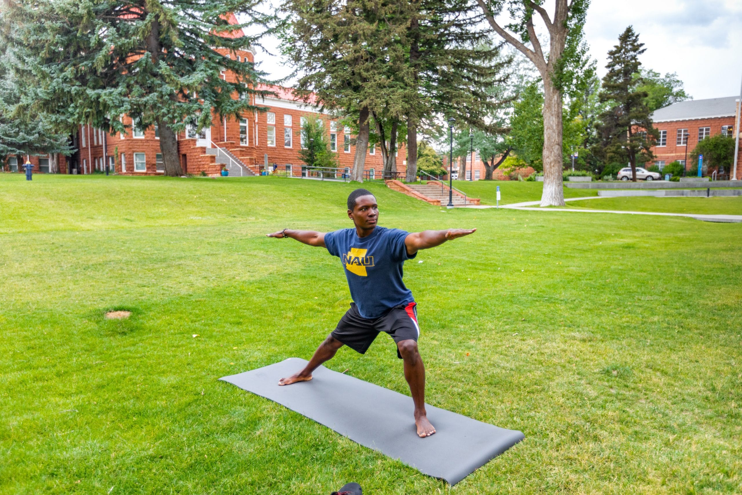 Student does yoga in grass outside.