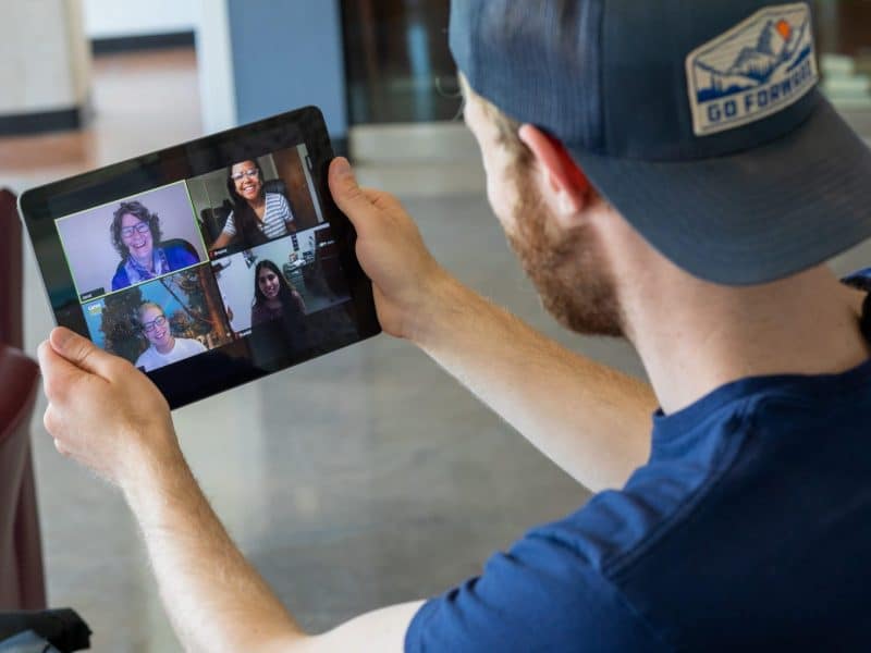Student talks with professor and classmates through a video call on IPad.