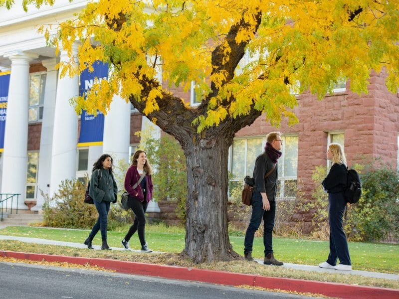 Four students walking through Flagstaff campus in the fall.