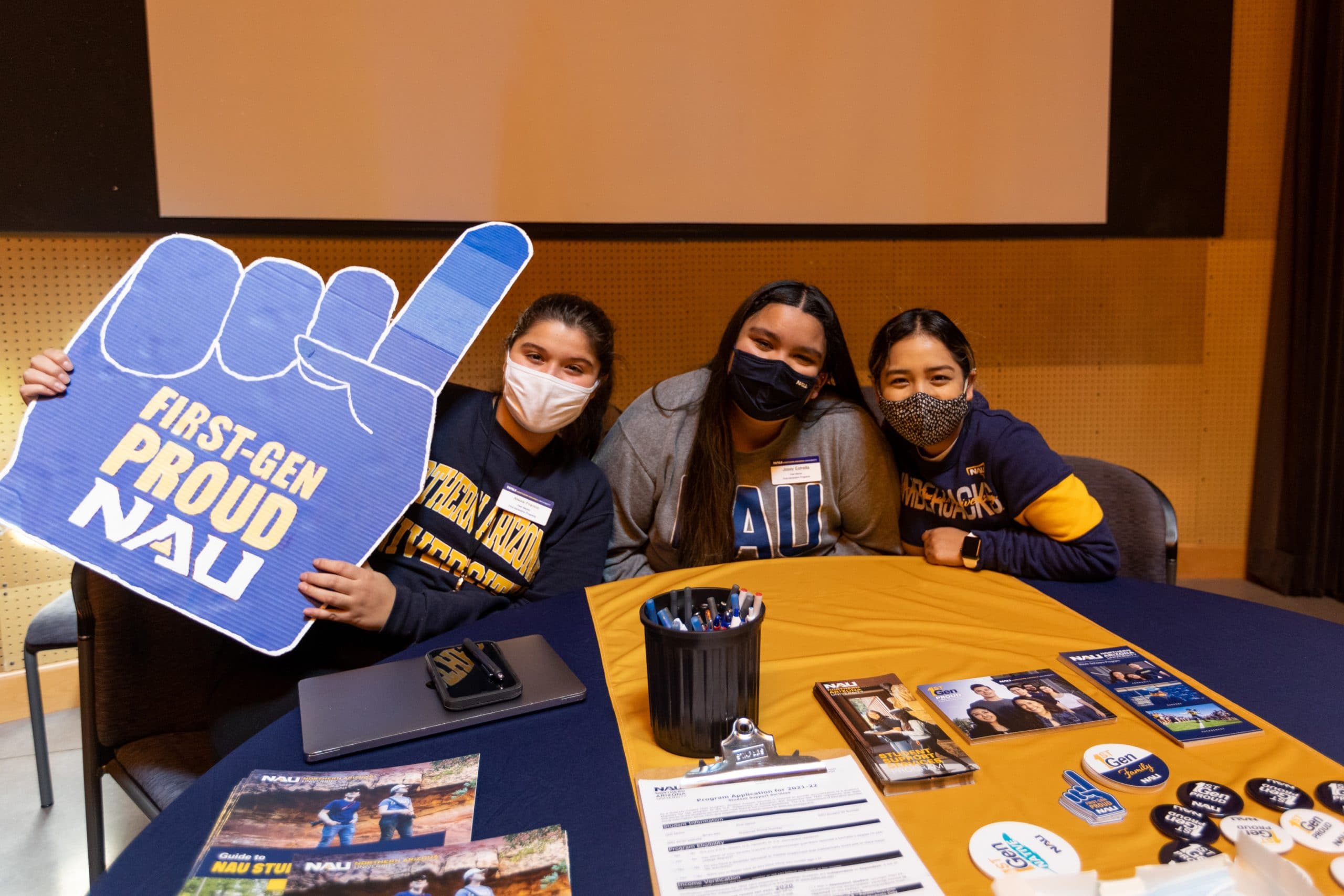 First-gen students sit at a table with a large foam finger.