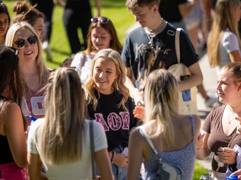 Sorority students meet and greet outside on a lawn.