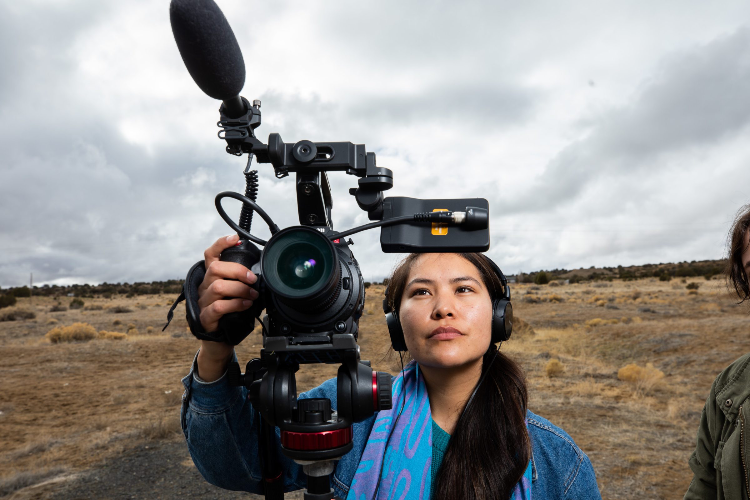 Tinia Witherspoon is standing in the desert and holding a filmmaking camera