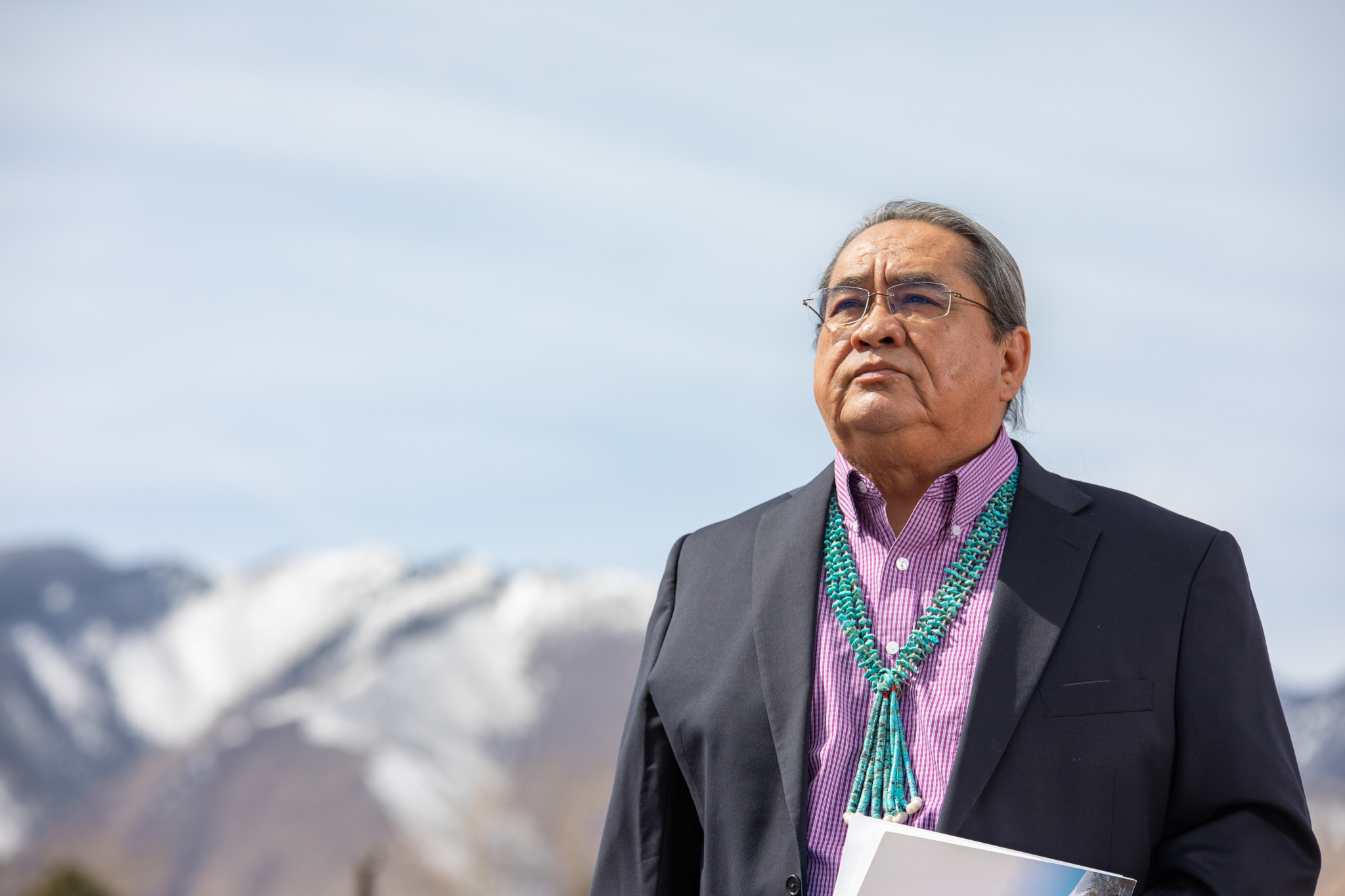Manley Begay stands outside with a mountain in the background.