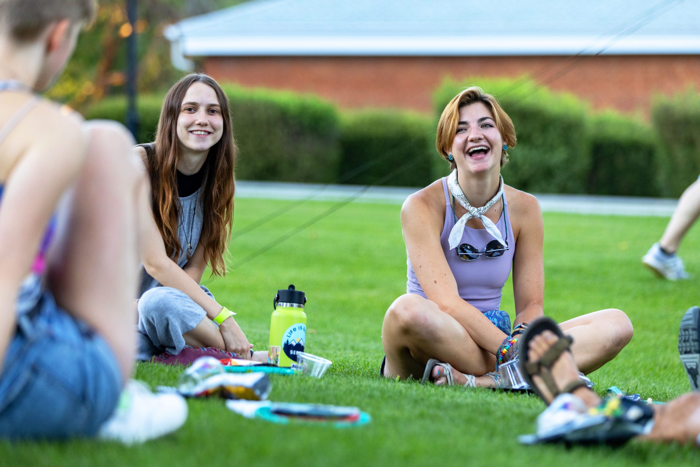 Students sitting on grassy field smiling