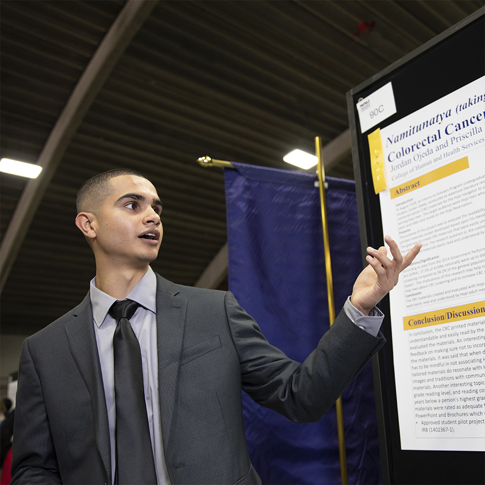 Student points to a poster at the symposium