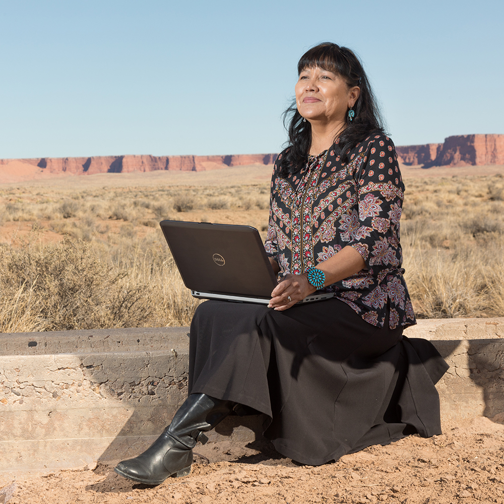 Priscilla Sanderson sits outside with a laptop