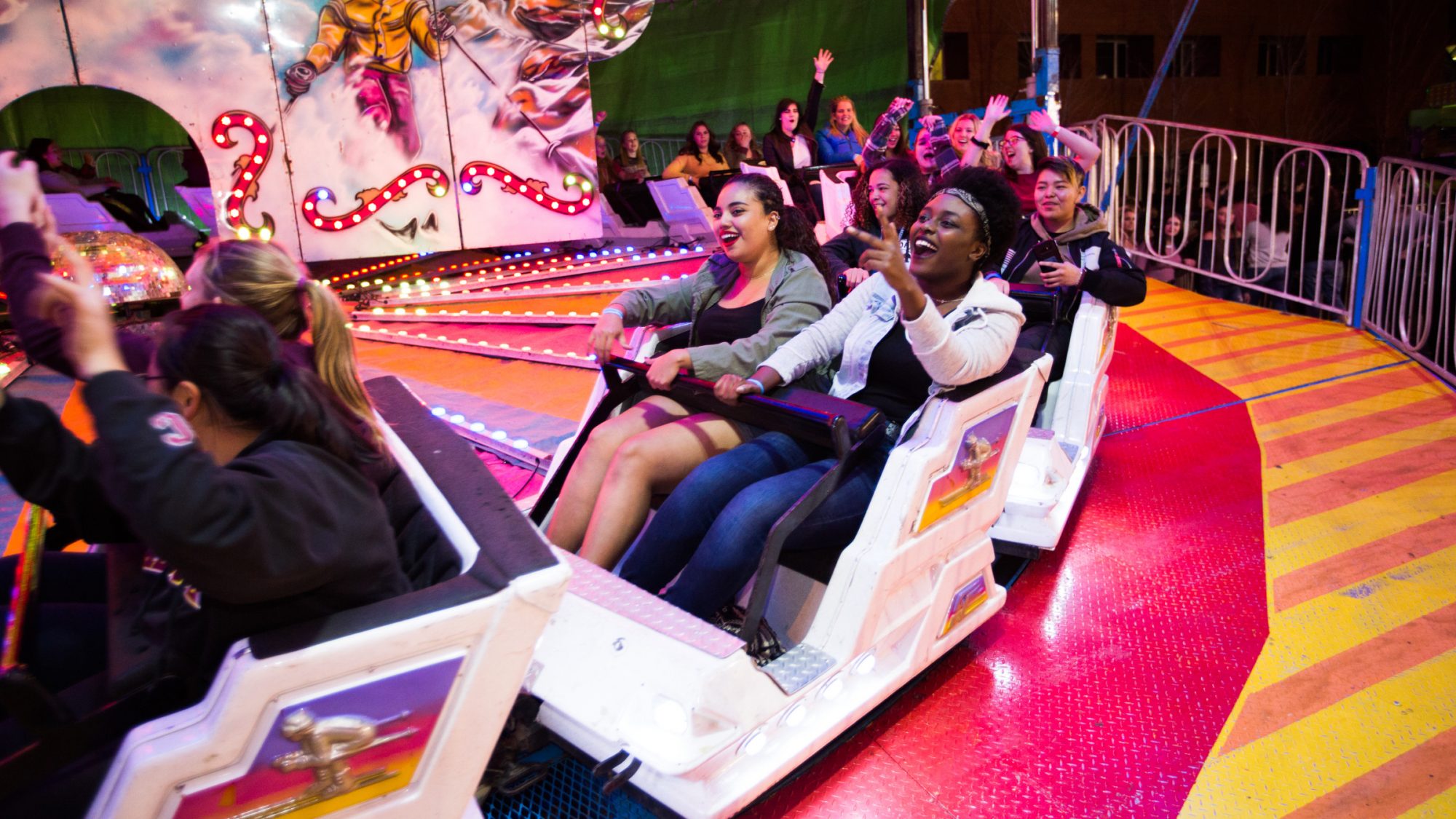 Students smiling and hands in the air while riding N A U carnival ride.