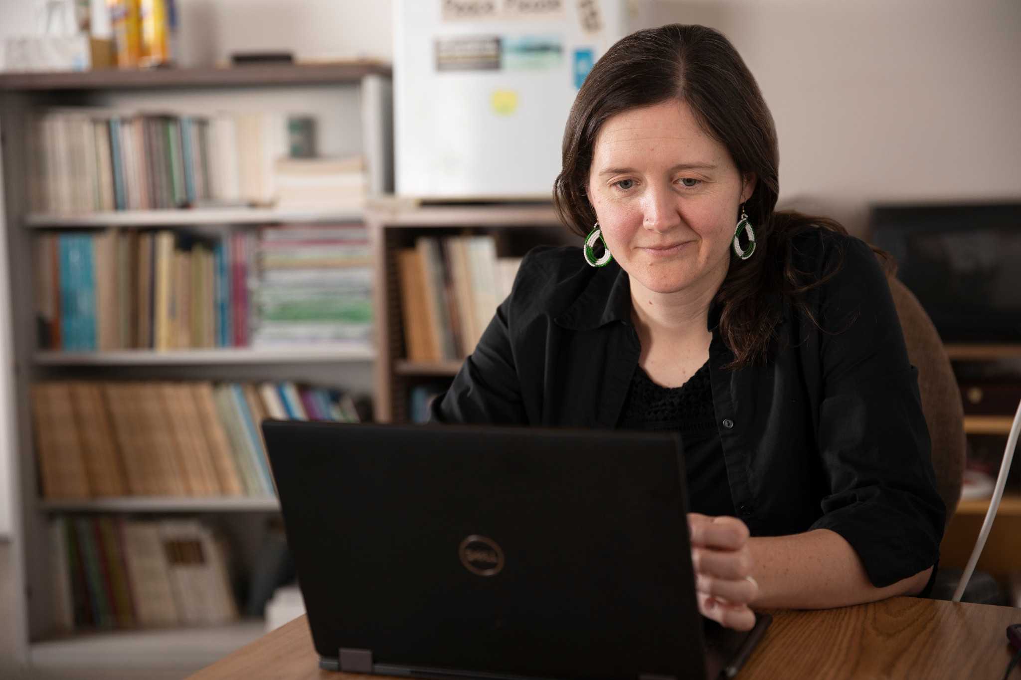 Associate Professor of Anthropology, Emery Eaves, working on their laptop