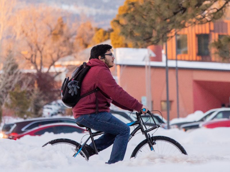A student riding their bike on the N A U campus is in the winter