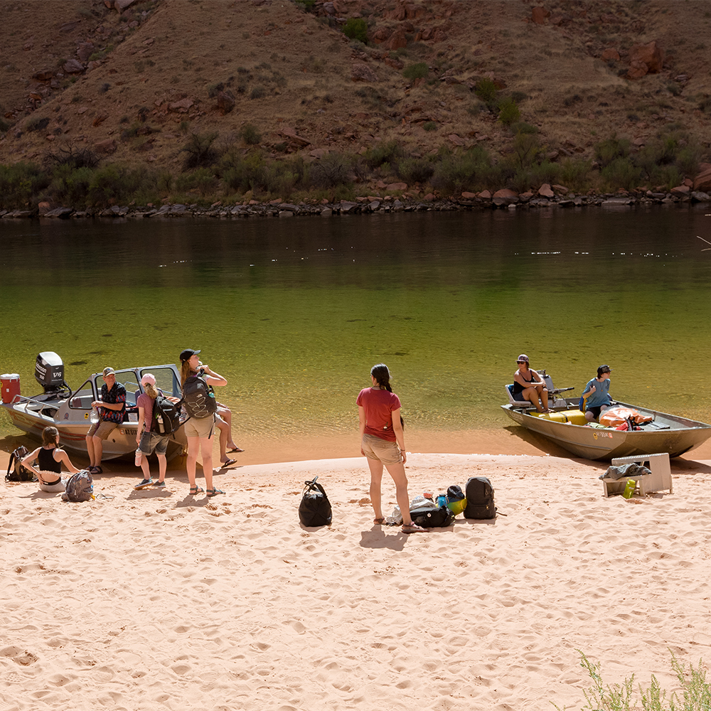 Students with boats on a sandy shore of the Colorado River