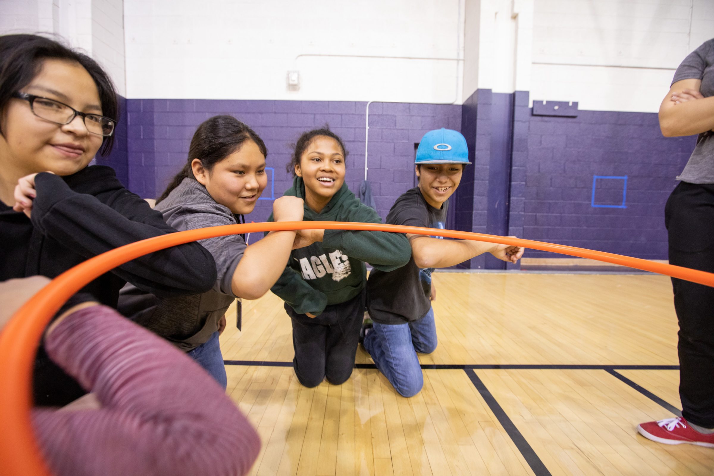 A group of children push against a hula hoop.