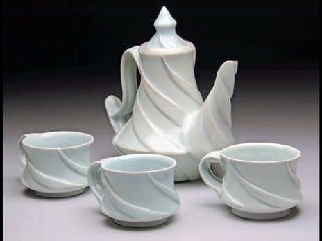 Teal ceramic teapot with three cups by student Kenny Tinklenberg